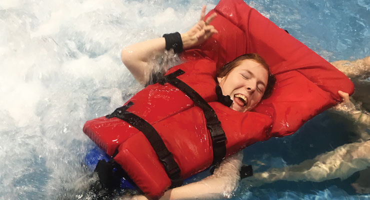Girl wearing life jacket in pool, smiling