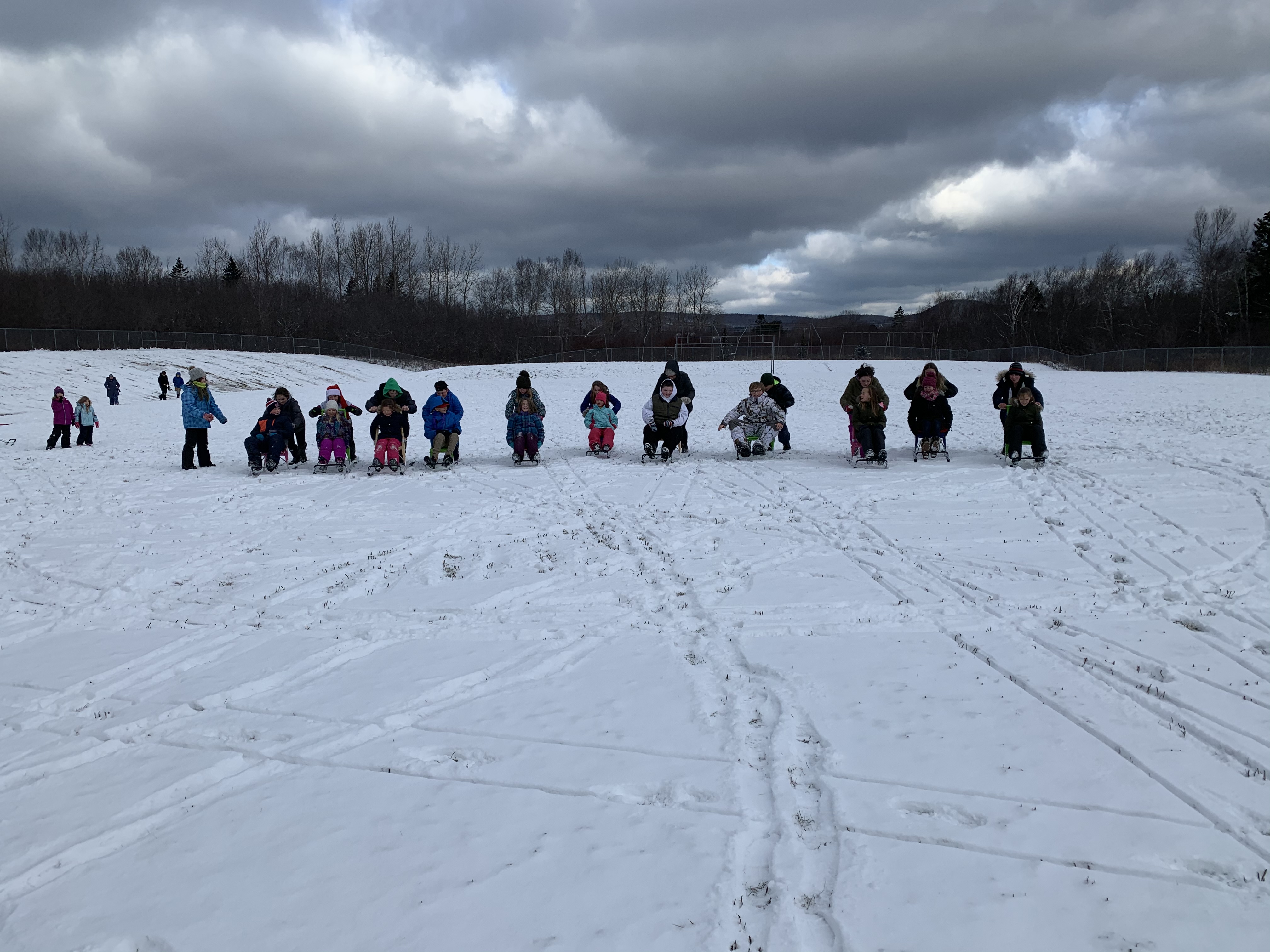 Group of kids with their partners using sled in the snow