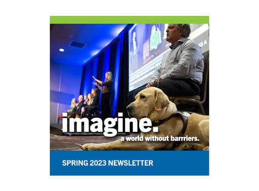 A man who is blind with a guide dog laying next to him. They are at a conference with a panel of speakers next to them. White text reads, "imagine a world without barriers. Spring 2023 Newsletter." 
