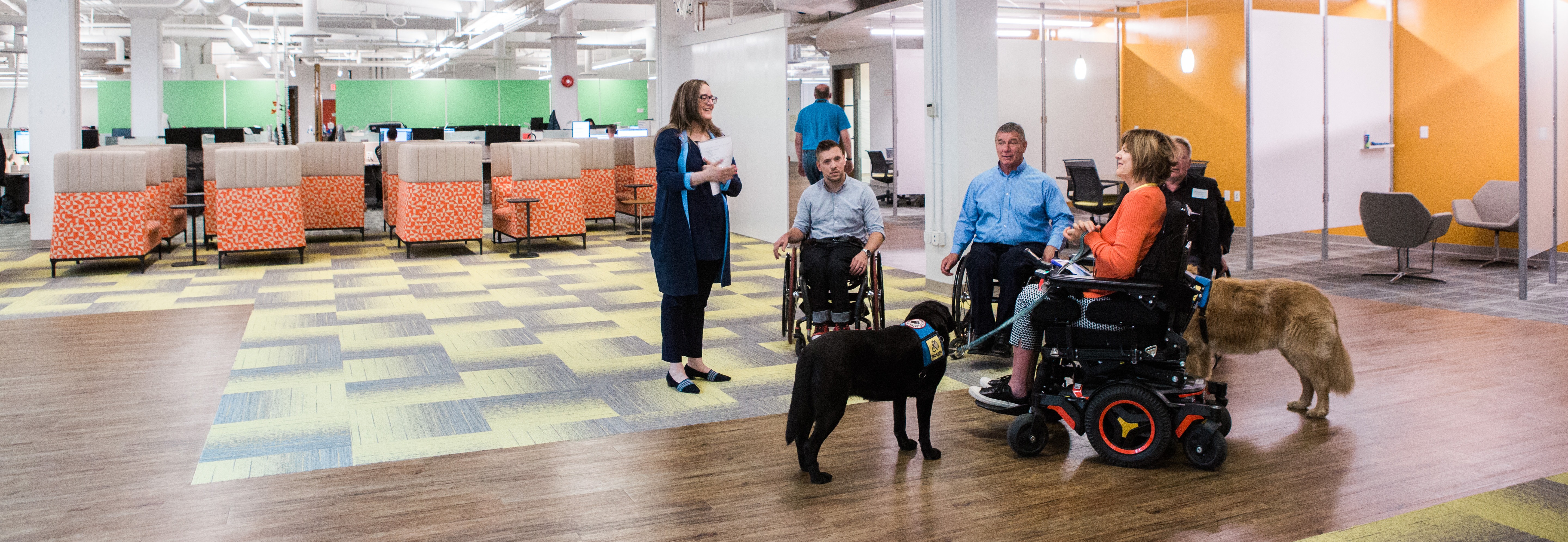 Rick Hansen, Marco Pasqua, and three other people talk in a group in a big office space.