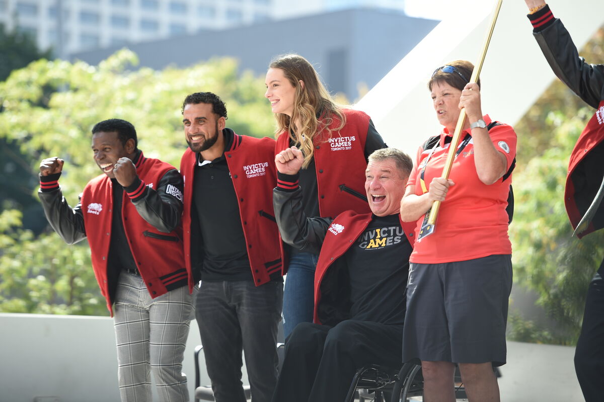 Rick as an Ambassador for the 2017 Invictus Games. HE is pictured smiling and cheering with 4 others. From L to R: Michael Pinball Clemens, Dwayne De Rosario, Penny Oleksiak, Rick Hansen, unknown.