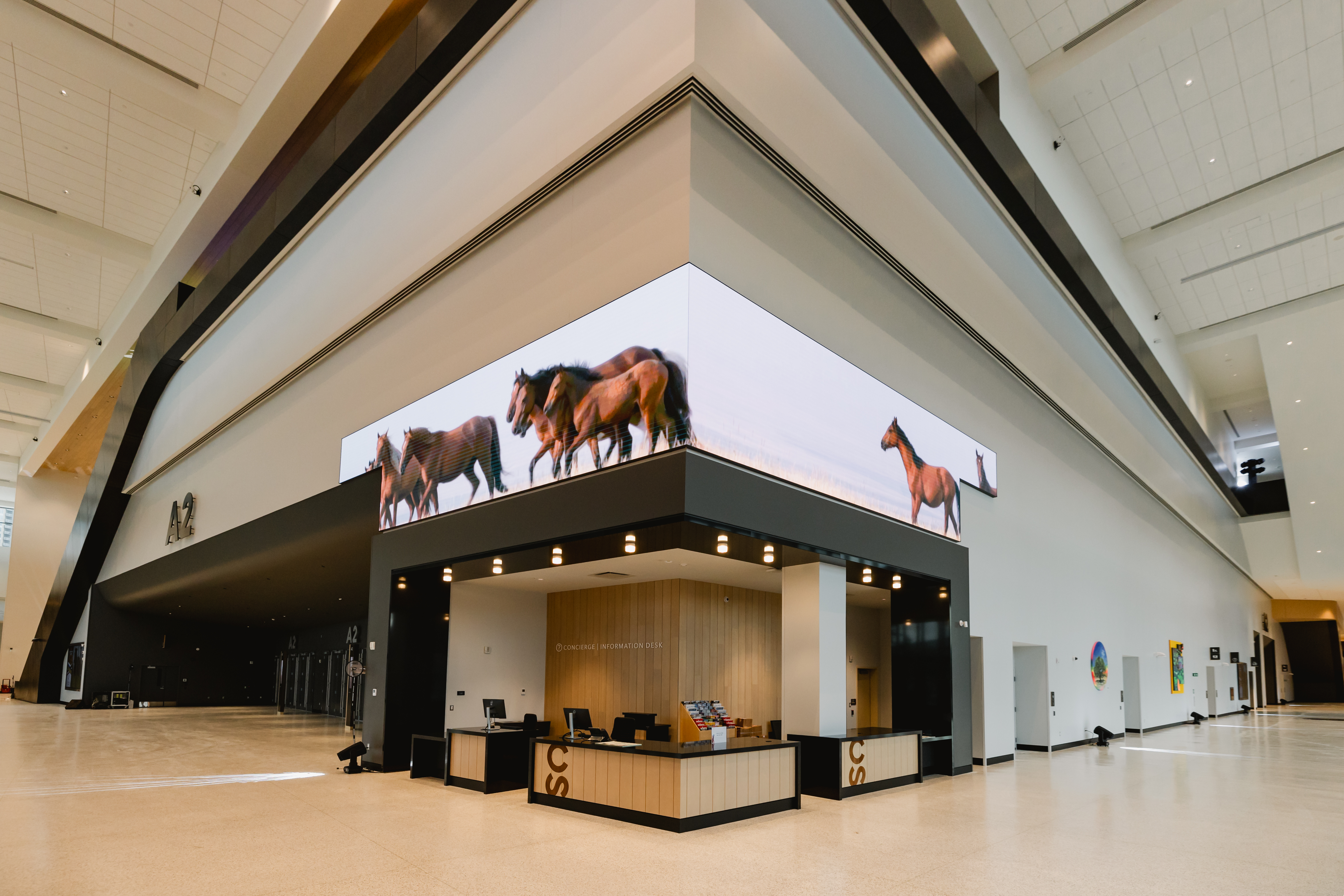 The lobby of the BMO Convention Centre with a wide, open area and high ceilings. There are black, neutral, and white interior colours.