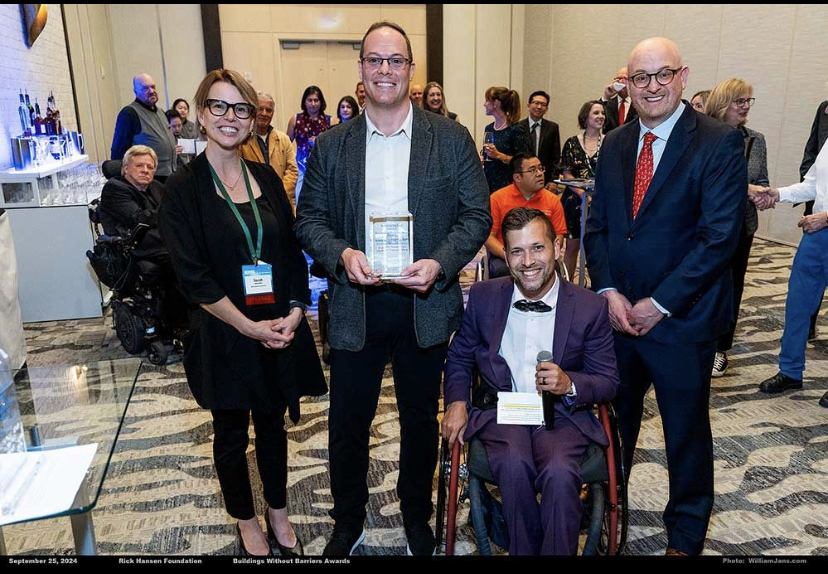 A photo of Adam Taylor accepting the Accessibility Progress Award at the BOMEX Gala. Left to Right: Sarah McCarthy, Adam Taylor, Marco Pasqua, Benjamin Shinewald.