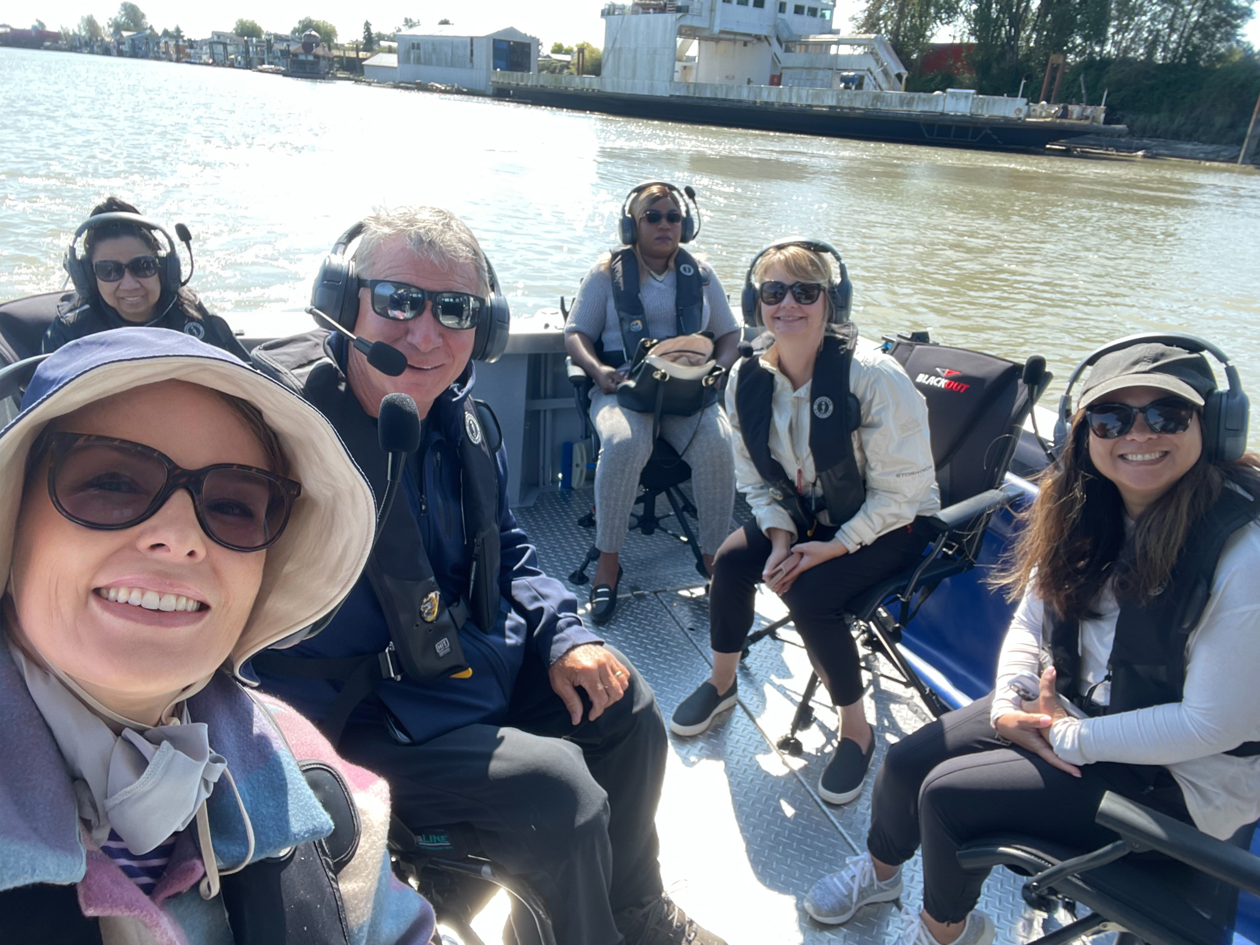 RHF staff with Rick Hansen wearing headsets and sitting in the new AOP boat.