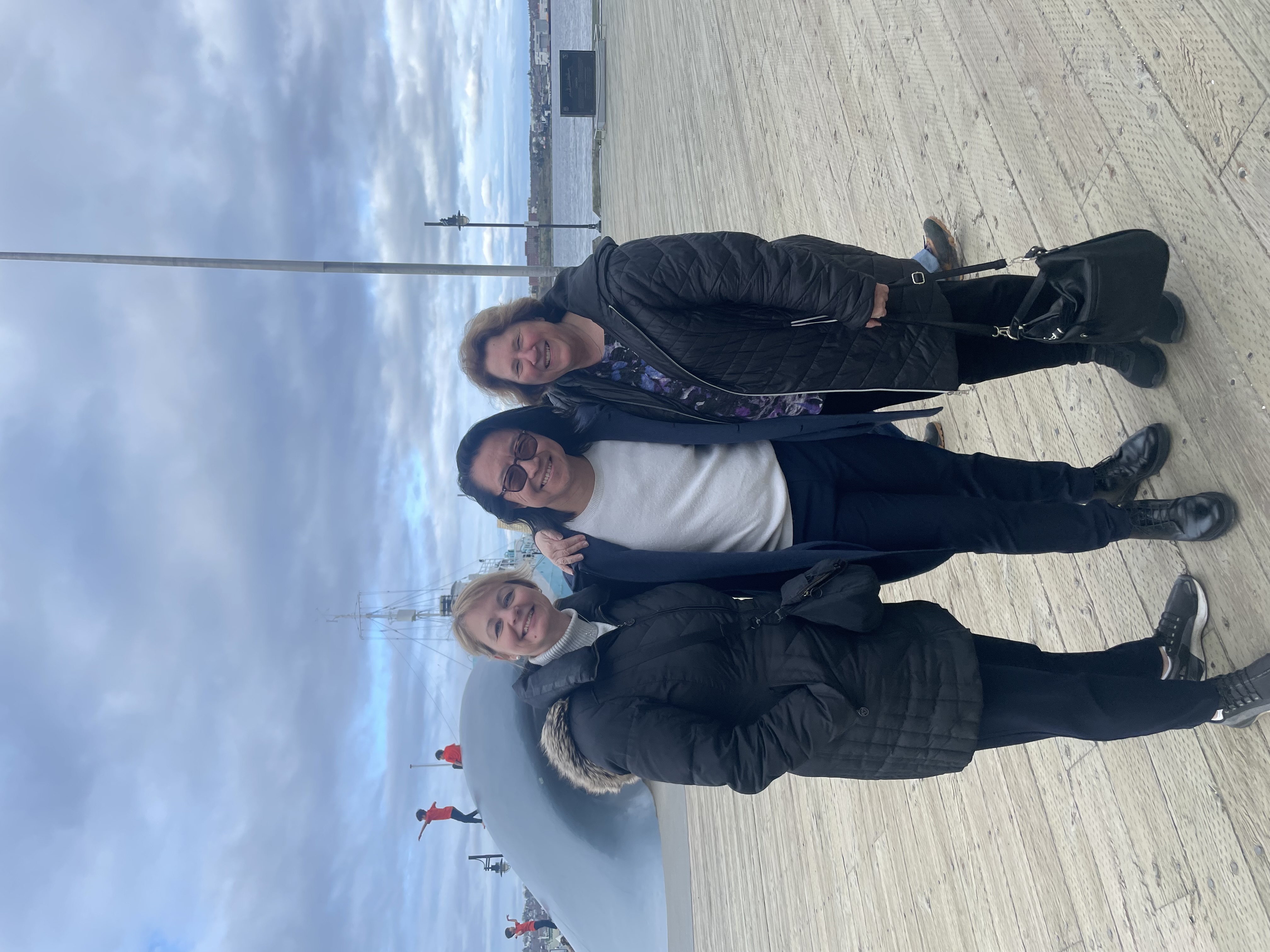 Laura McBride, Kevin Ng, and Doramy Ehling stand together for a photo outside. They are wearing long, dark-coloured coats for the cold weather.