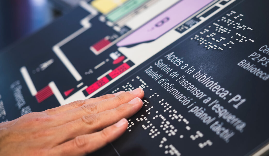 a close up of a hand touching braille signage