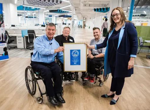 Group holds up plaque, including Rick Hansen