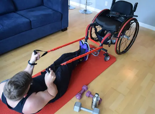 Marco on yoga mat pulling wheelchair using exercise bands 