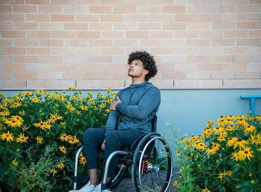 Paulo Guerro beside a garden  using his wheelchair.