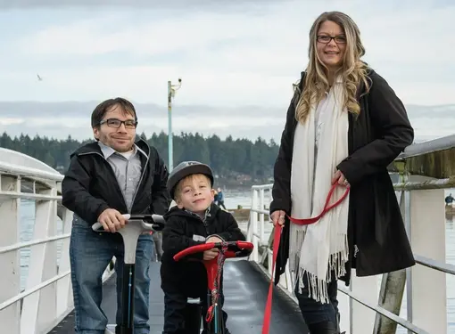 Jim, his wife and son on a dock using motorized scooters