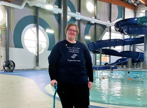 Alexis standing next to a pool, wearing a shirt saying you know who has genetic mutations? superheros