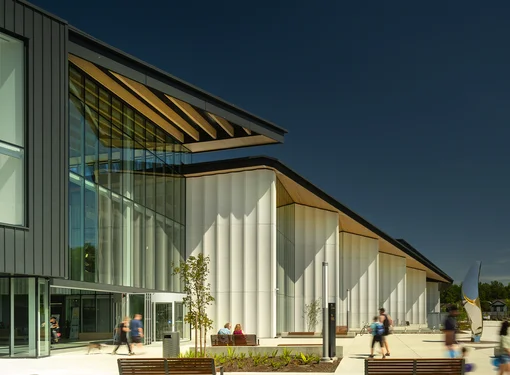 An exterior photo of  the təməsew̓txʷ Aquatic and Community Centre showing a variety of people outside the new building.