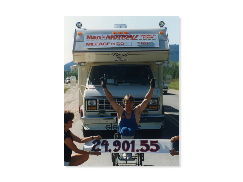 Rick Hansen during the Man in Motion World Tour raising his arms in celebratory manner as he wheels into a 24,901.55 km sign. 