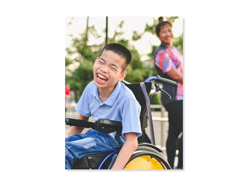 Child in a wheelchair laughing.