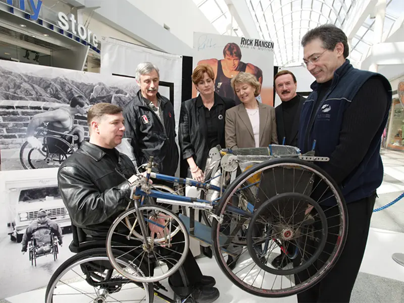 Rick Hansen et son équipe devant une exposition en l’honneur de Rick Hansen. 