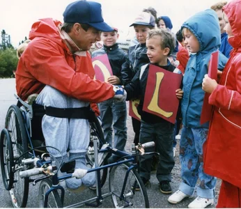 young rick hansen shakes hands with school aged children on his mn in motion world tour