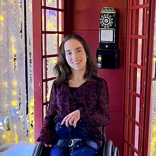 Woman using a wheelchair in front of red british phone booth