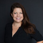 Headshot, woman with brown hair smiling, wearing black shirt. 